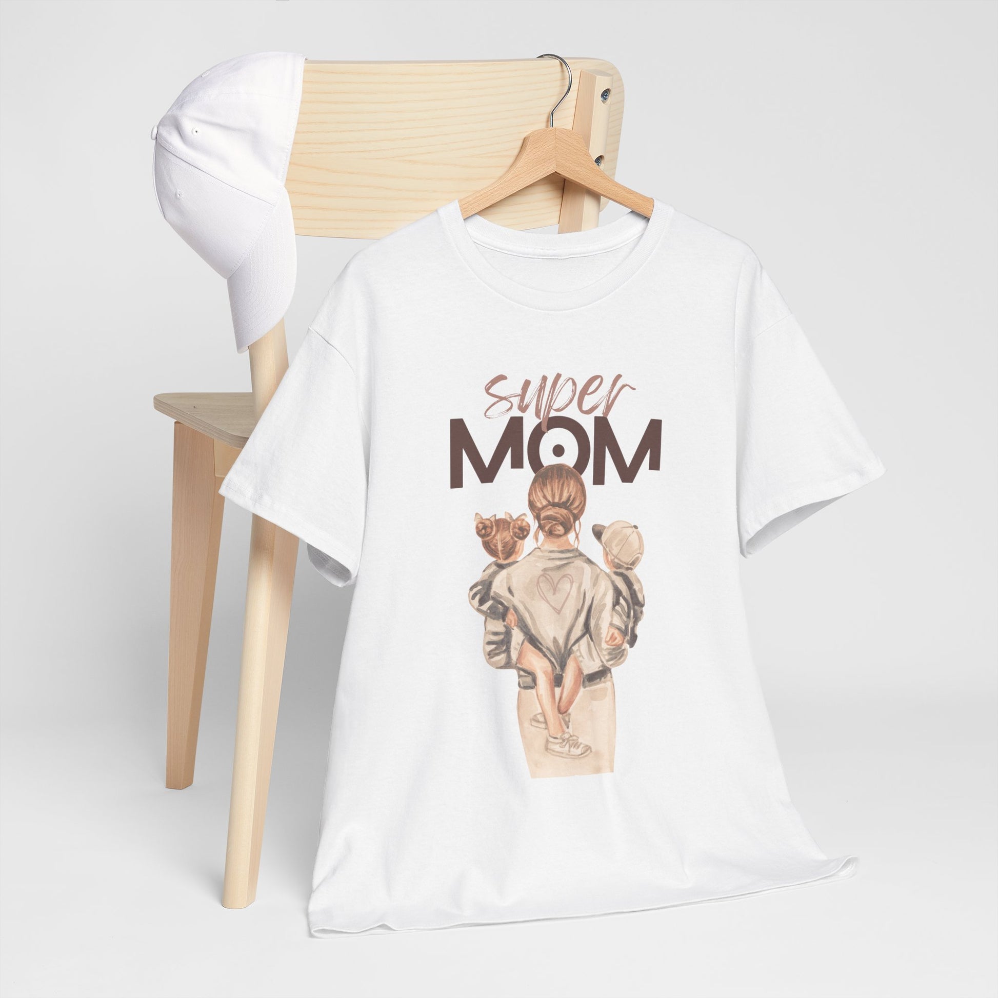 White celebration shirt for moms with super mom graphic hanging on wooden chair with white cap